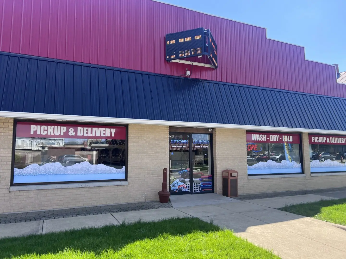 Exterior of Uptown Laundry in Bucyrus, Ohio, showing the storefront with pickup and delivery signage, wash–dry–fold windows, and the main entrance.