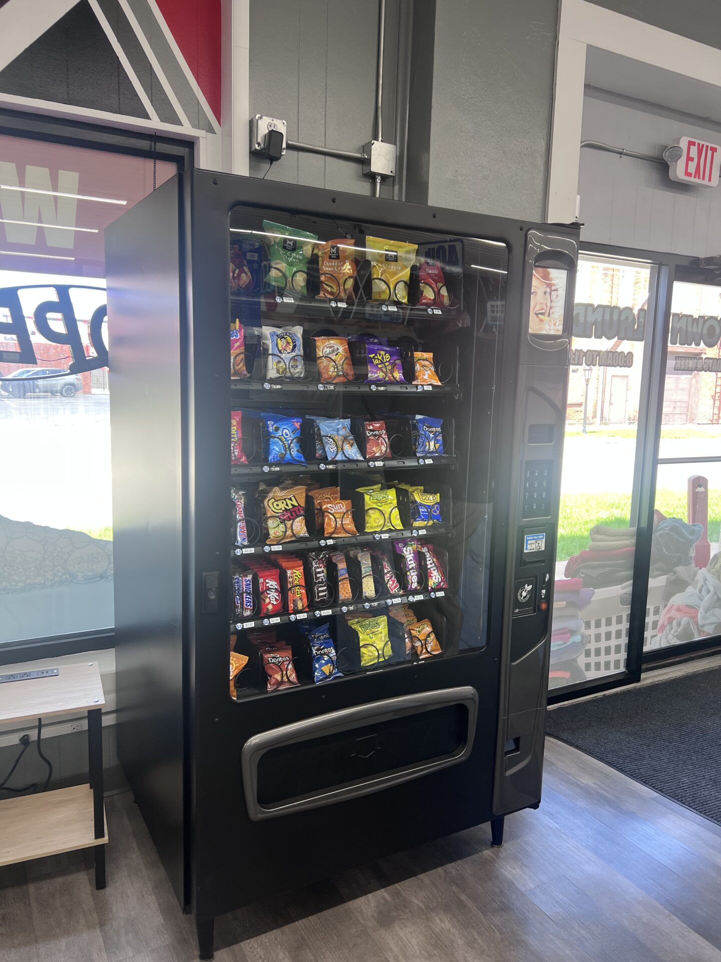 Snack vending machine inside Uptown Laundry offering a variety of snacks while you wait.