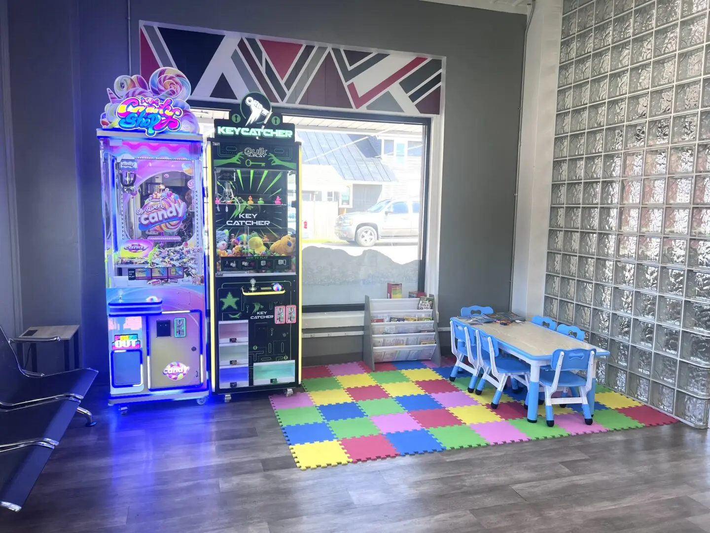Kids’ play area inside Uptown Laundry featuring arcade-style games and a small table with seating.