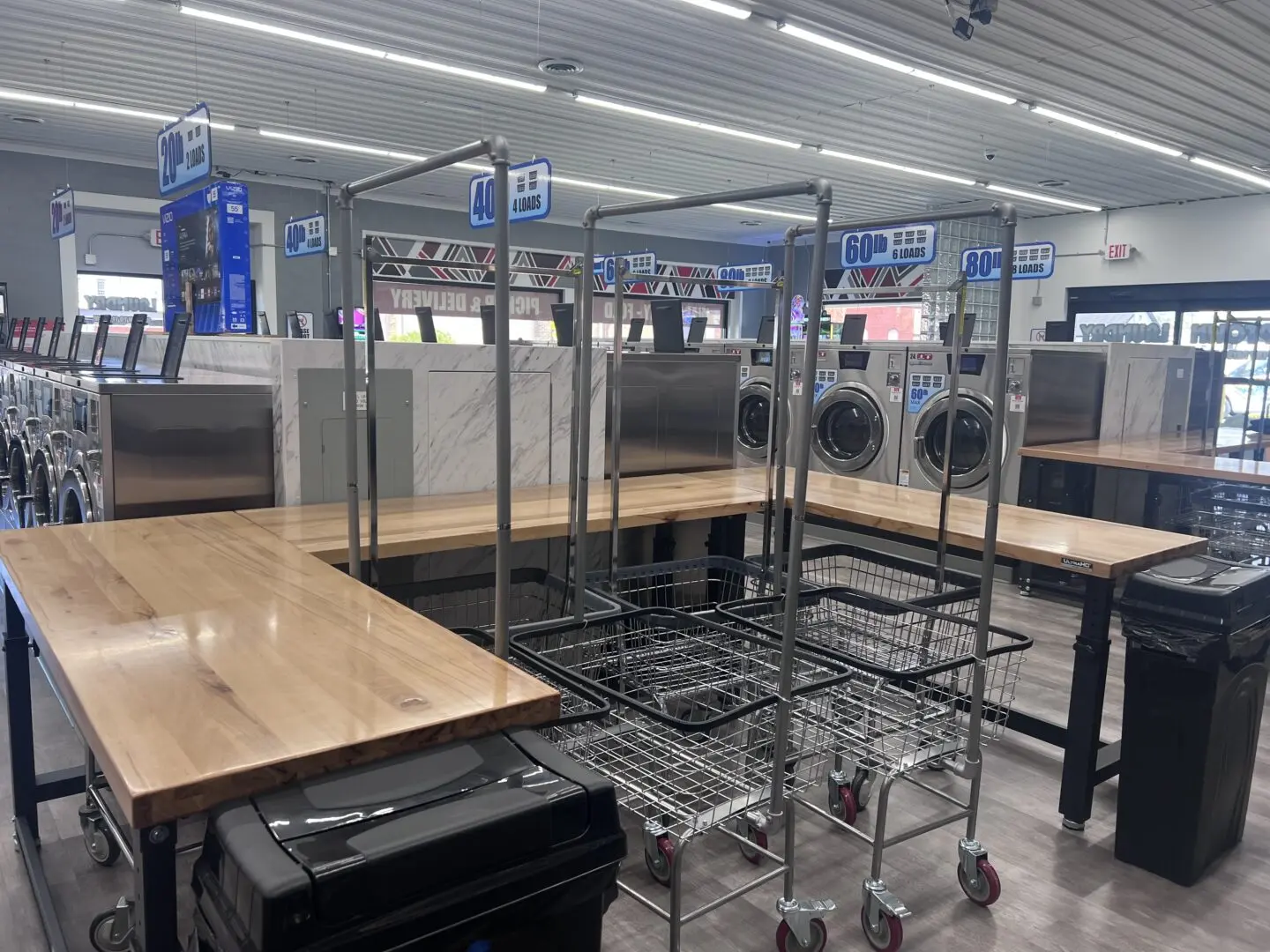 Interior view of Uptown Laundry showing large folding tables and rolling laundry carts for customer use.